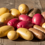 Различные сорта картофеля на деревянном столе — ранние, средние и поздние виды.